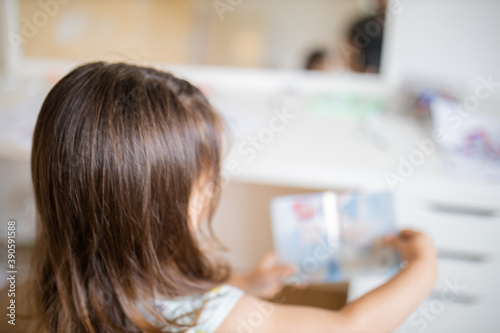 Little girl looking at an American passport in front of a desk and a mirror