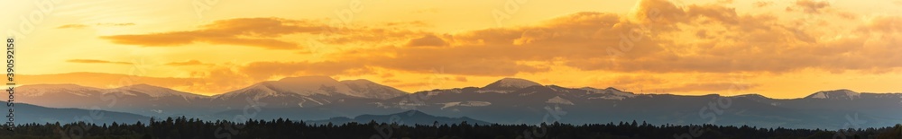 Styrian Lavanttaler Alps covered with snow in orange light of sunset. Background or banner