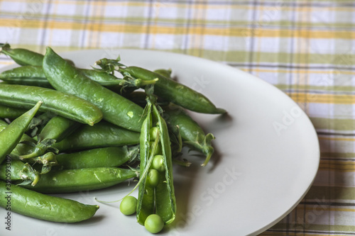Green peas only from the kitchen gardenon a plate that is on a tablecloth in a box