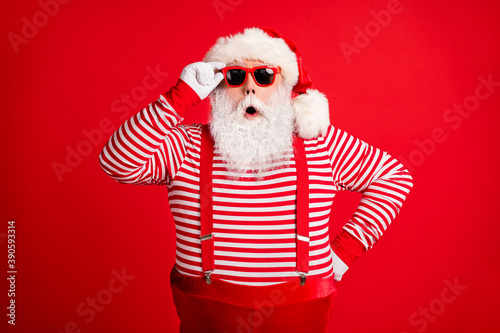 Portrait of his he nice handsome amazed wondered grey-haired Santa wearing touching sunglasses winter incredible bargain isolated over bright vivid shine vibrant red color background © deagreez