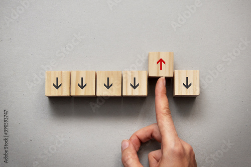Wooden cubes with down arrows and one cube with a red arrow up. Choosing an individual path against public opinion photo