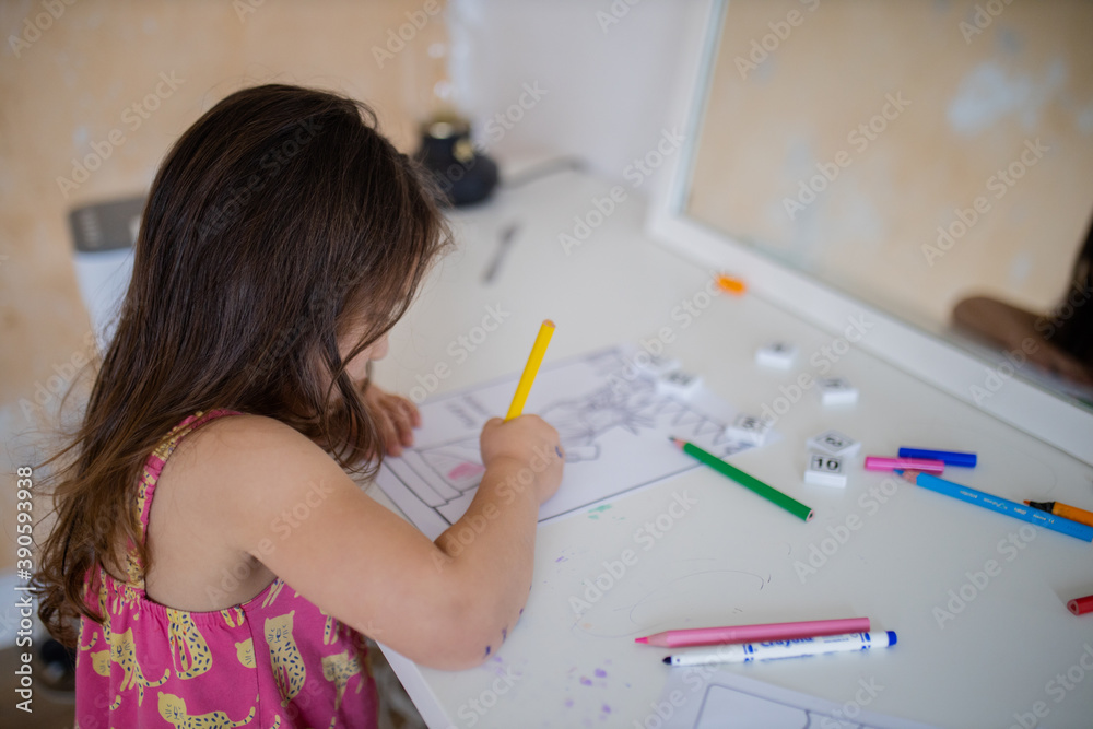 Little girl coloring an image of the Statue of Liberty with a yellow pencil Little girl coloring an image of the Statue of Liberty with a yellow pencil