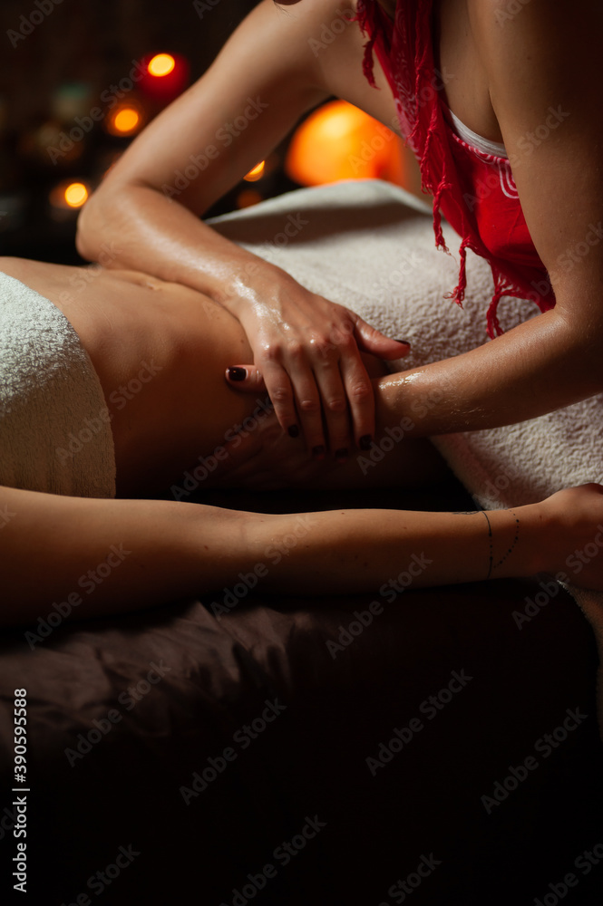 Obraz premium Close up of therapist doing stomach massage on woman in spa against dark background.