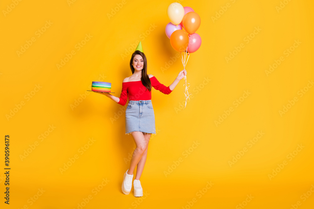 Full body size photo of cute pretty charming young girl beaming smiling hold balloons cake wear cone shirt open shoulders denim mini sneakers skirt isolated bright yellow color background Full body size photo of cute pretty charming young girl beaming smiling hold balloons cake wear cone shirt open shoulders denim mini sneakers skirt isolated bright yellow color background