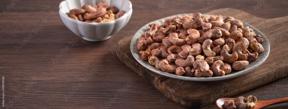 Cashew nuts with peel in a plate on wooden tray. Cashew nuts with peel in a plate on wooden tray.