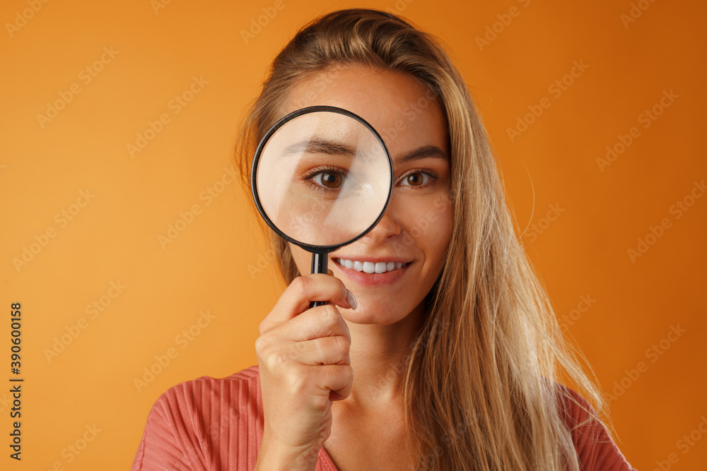 Beautiful young blonde woman looking on you through magnifying glass Beautiful young blonde woman looking on you through magnifying glass