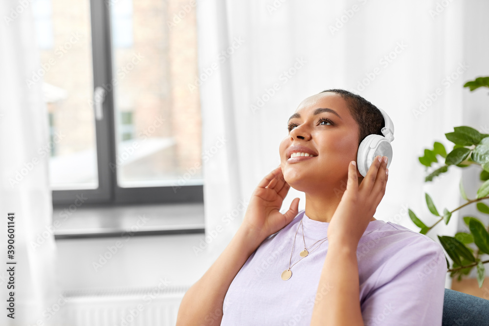 people, technology and leisure concept - happy young african american woman in headphones listening to music at home people, technology and leisure concept - happy young african american woman in headphones listening to music at home