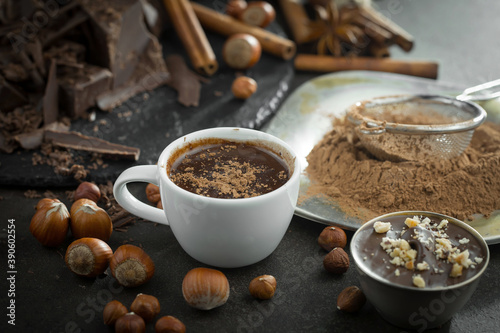 Hot chocolate on an old background in a composition with cocoa beans and nuts.