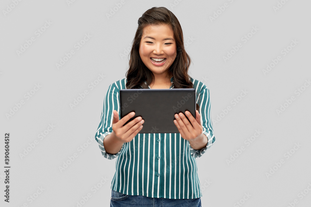technology and people concept - happy asian woman using tablet computer over grey background technology and people concept - happy asian woman using tablet computer over grey background