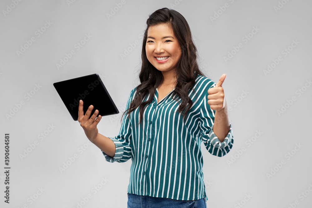technology and people concept - happy smiling asian woman with tablet computer showing thumbs up over grey background technology and people concept - happy smiling asian woman with tablet computer showing thumbs up over grey background