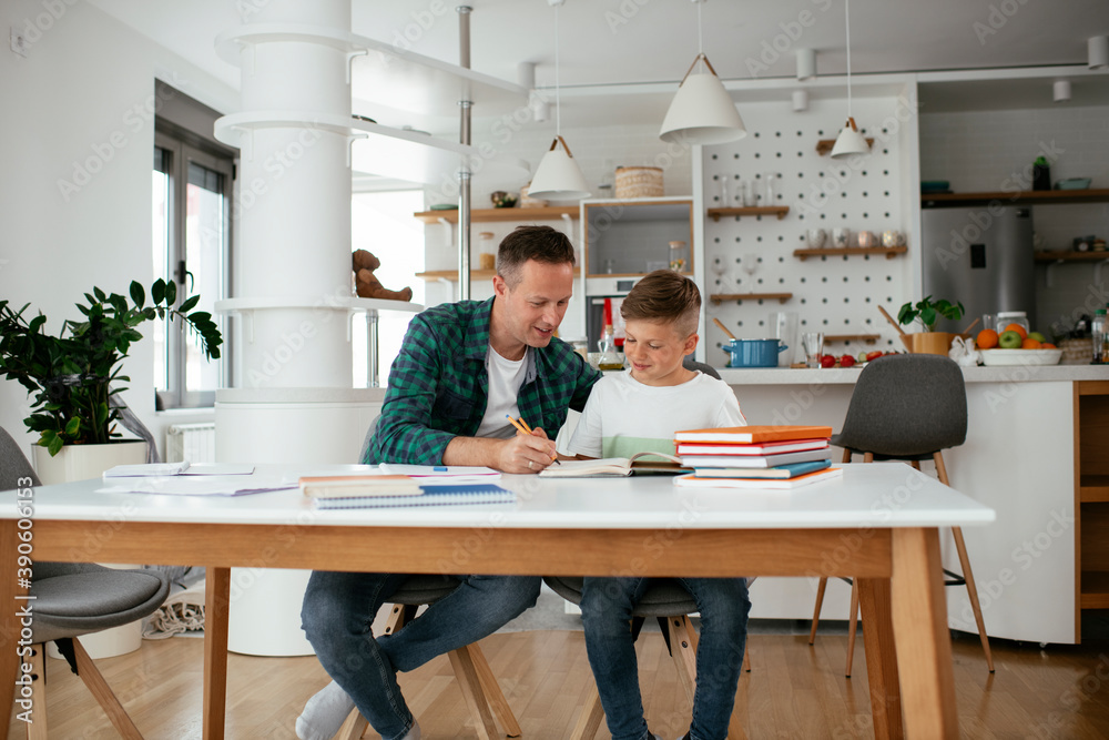 Father helping his son with homework at home. Little boy learning at home.