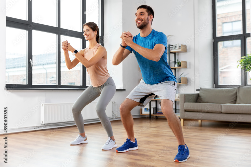 sport, fitness, lifestyle and people concept - smiling man and woman exercising and doing squats at home sport, fitness, lifestyle and people concept - smiling man and woman exercising and doing squats at home