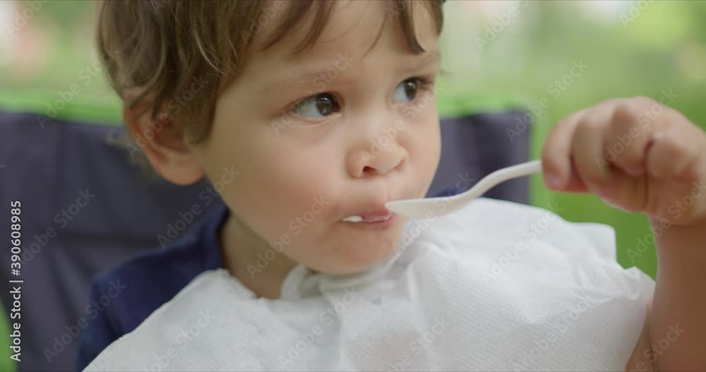 Litte girl eating ice cream with spoon in the park. Litte girl eating ice cream with spoon in the park.