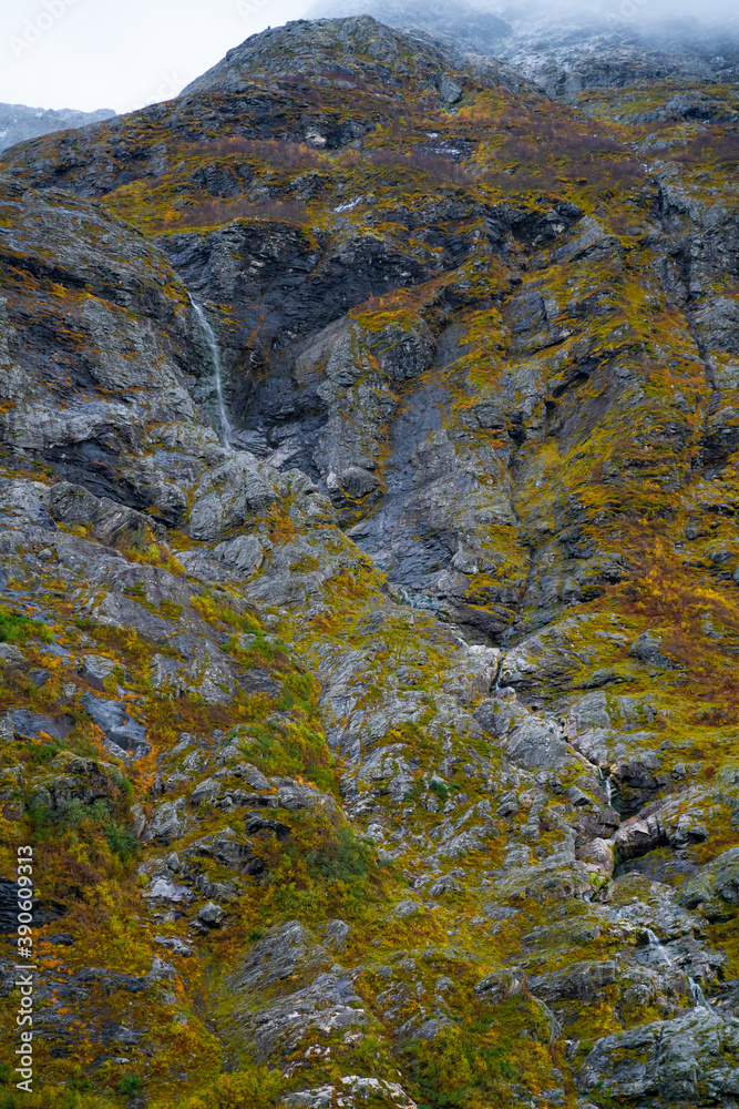 Tall serene waterfall cascading down a steep mountain slope in lush autumn colors. Tall serene waterfall cascading down a steep mountain slope in lush autumn colors.