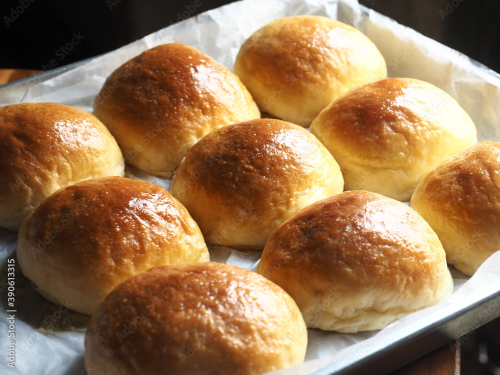 Shiny golden brown bread rolls in baking tin