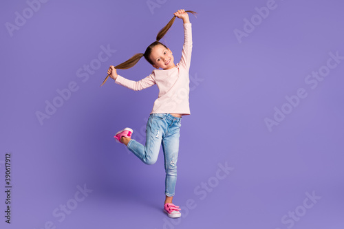 Full size photo of careless happy girl hold hands pigtails wear jeans sweater isolated on purple color background photo