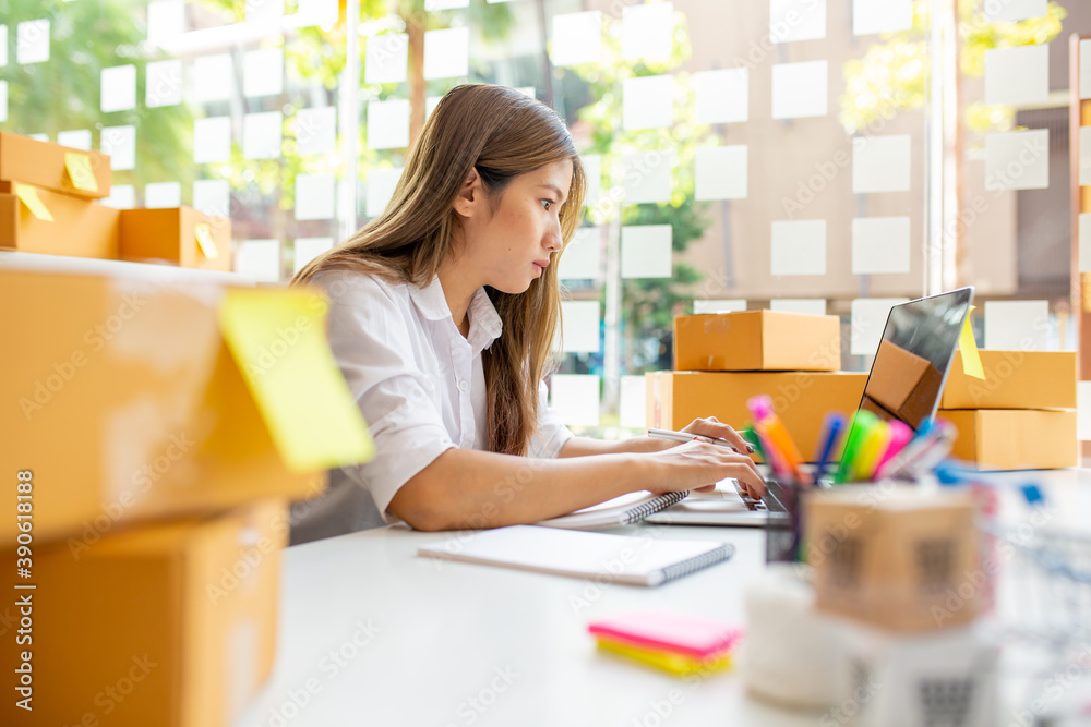Starting Small business entrepreneur SME freelance,Portrait young woman working at home office, BOX,smartphone,laptop, online, marketing, packaging, delivery, SME, e-commerce concept  