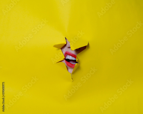 Broken yellow background with a woman's mouth poking out with red lips