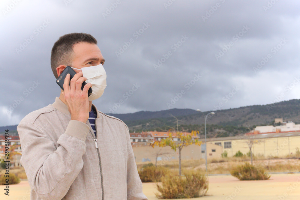 Man wearing reusable facial mask using phone at the street. Man wearing reusable facial mask using phone at the street.