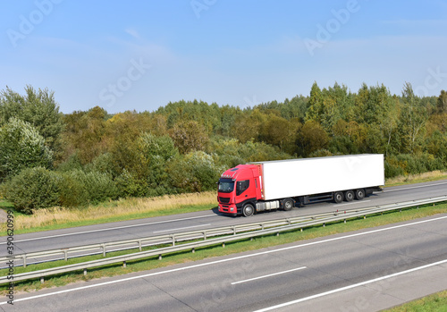 Truck with semi-trailer driving along highway. Goods delivery by roads. Services and Transport logistics