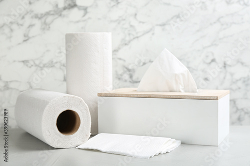 Clean napkins, box with tissues and rolls of paper towels on light table