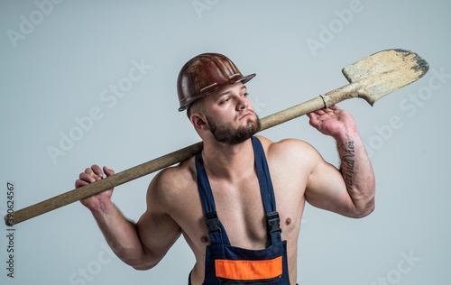 Man for any job. muscular man on construction site. handsome building worker in hard hat. labor day. athletic guy wear safety helmet. male engineer on work with shovel. sexy builder in boilersuit