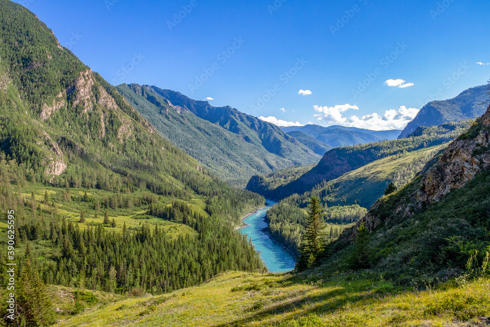 The blue river flows in the distance surrounded by mountains