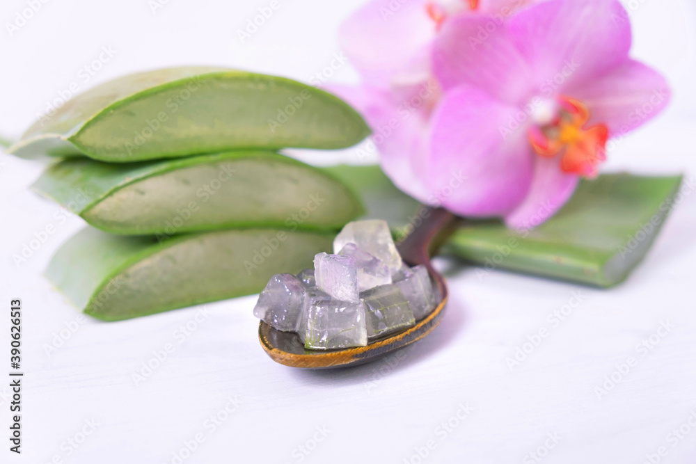 chopped small pieces of aloe vera in a wooden spoon, orchid and pieces of aloe vera