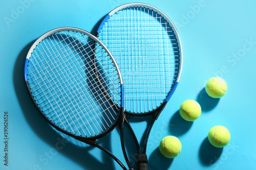 Tennis rackets and balls on blue background, flat lay. Sports equipment