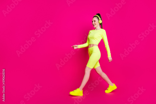 Full length body size view of her she nice attractive charming slender sporty cheerful girl listening pop rock melody music walking isolated bright vivid shine vibrant pink fuchsia color background