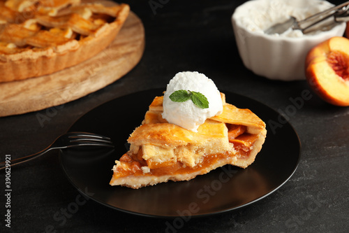Slice of delicious peach pie with ice cream on black table