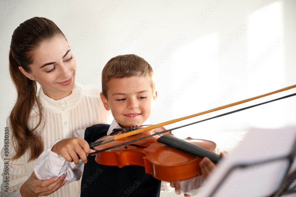 Young woman teaching little boy to play violin indoors Young woman teaching little boy to play violin indoors