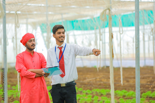 Young indian agronomist and farmer discuss at greenhouse or polyhouse