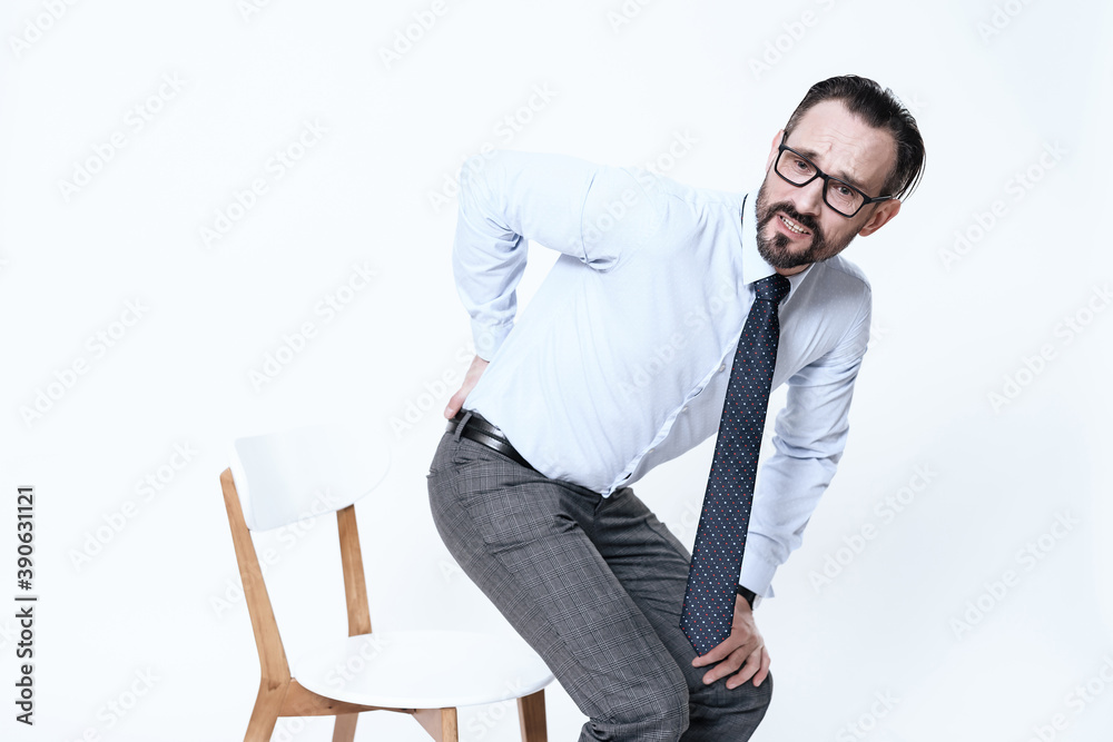 A man with a sore back rises from a chair. A man with a sore back rises from a chair.