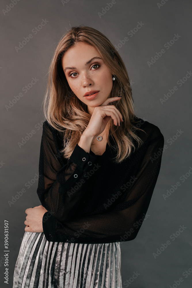 Elegant stylish female woman with blond hair wearing black blouse posing at camera over isolated grey background Elegant stylish female woman with blond hair wearing black blouse posing at camera over isolated grey background
