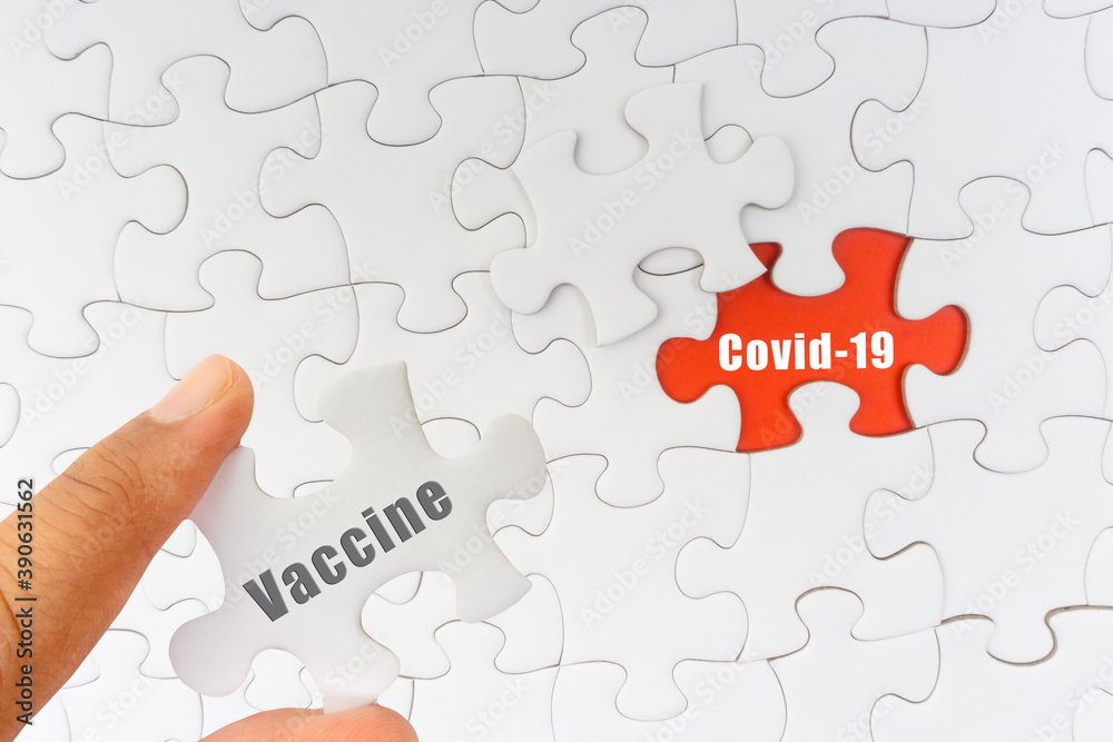 Fototapeta premium Hand holding jigsaw puzzle with text VACCINE and COVID-19. Covid-19 and Coronavirus concept