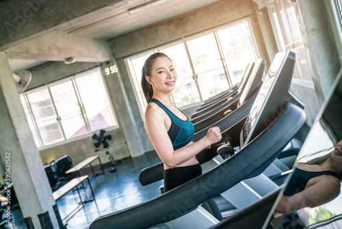 Asian woman jogging on a treadmill working out in gym