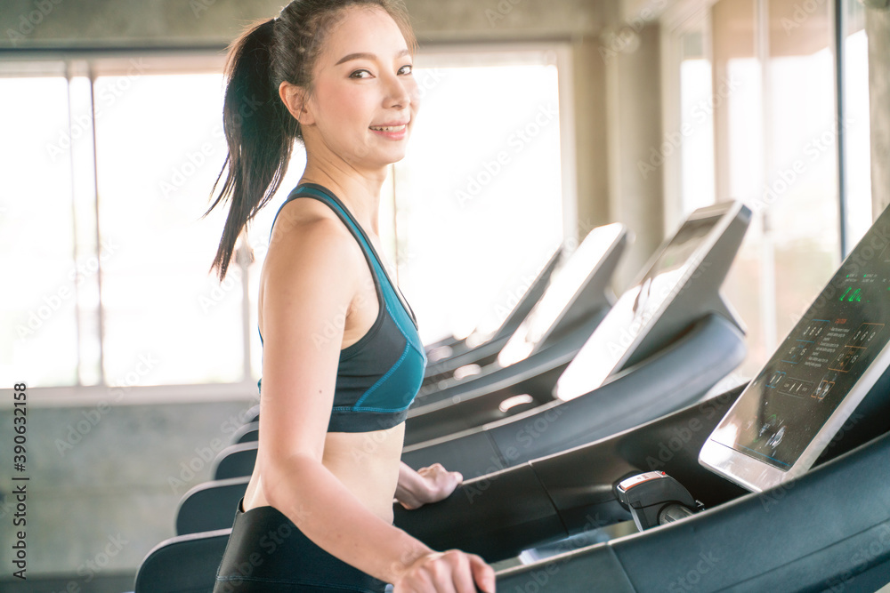 Fototapeta premium Asian woman jogging on a treadmill working out in gym