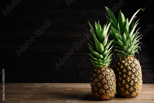 Fresh ripe juicy pineapples on wooden table. Space for text