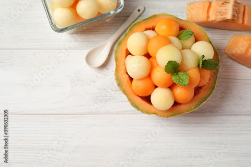 Different melon balls with mint on white wooden table, flat lay. Space for text