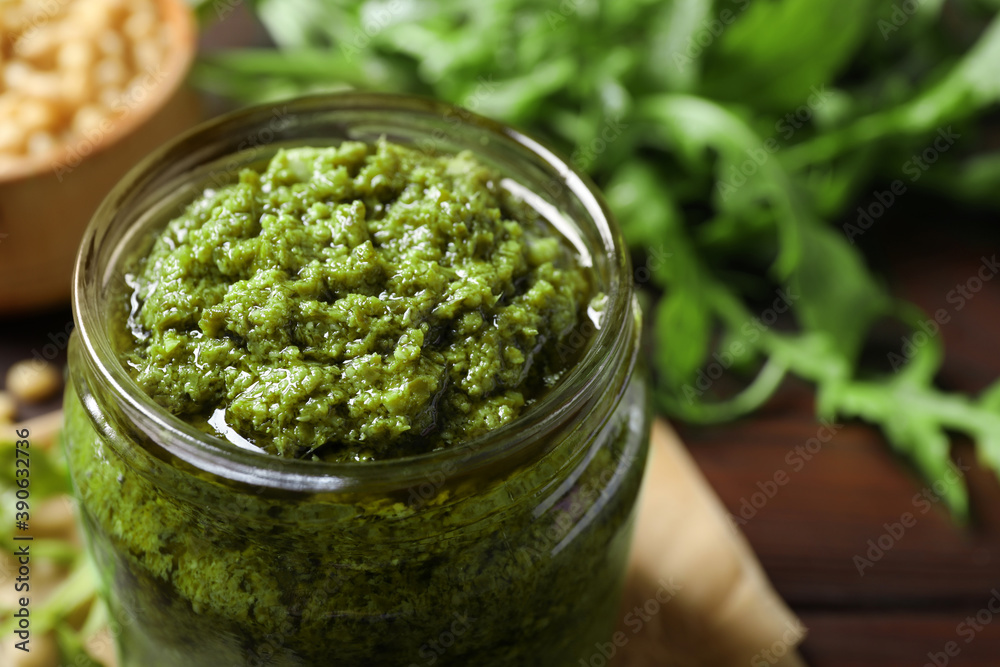 Jar of tasty arugula pesto on table, closeup Jar of tasty arugula pesto on table, closeup