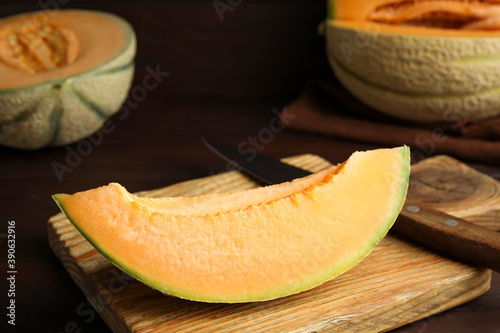 Slice of tasty fresh melon on wooden board, closeup