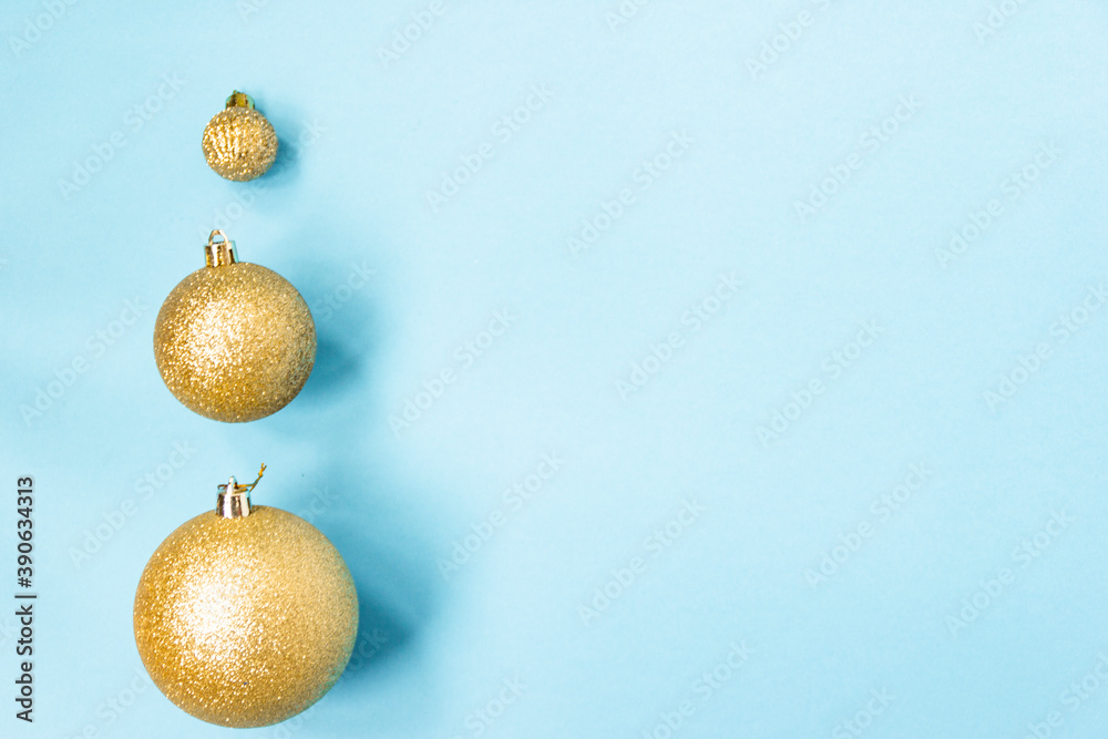 Three golden Christmas balls of different sizes are displayed in a row as a border on a blue background. New Year mood mok up. Copy space Three golden Christmas balls of different sizes are displayed in a row as a border on a blue background. New Year mood mok up. Copy space