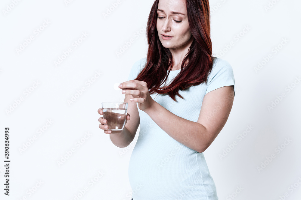 Girl looks into glass of water and pours medicine. Girl looks into glass of water and pours medicine.