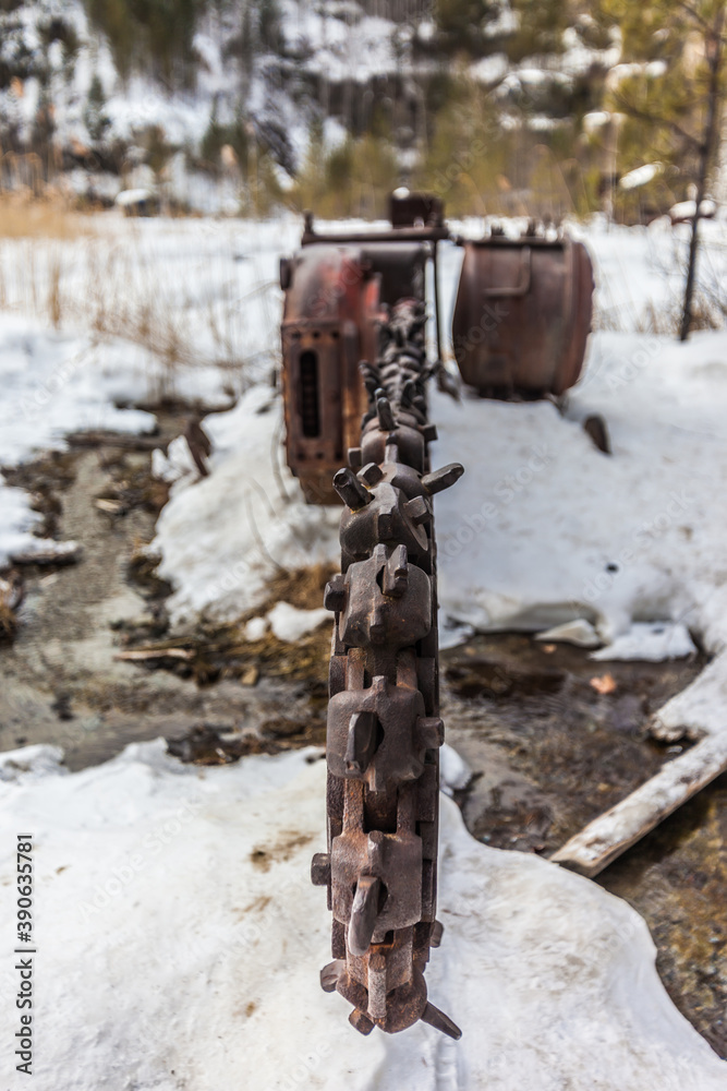 Abandoned industrial chain saw on the bottom of the quarry in winter Abandoned industrial chain saw on the bottom of the quarry in winter