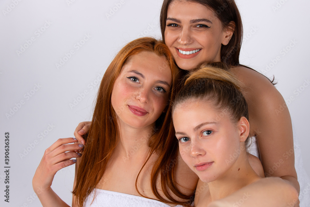 Three attractive girlfriends take selfies. Photo on a white background. Spa, beauty and relaxation concept. Three attractive girlfriends take selfies. Photo on a white background. Spa, beauty and relaxation concept.