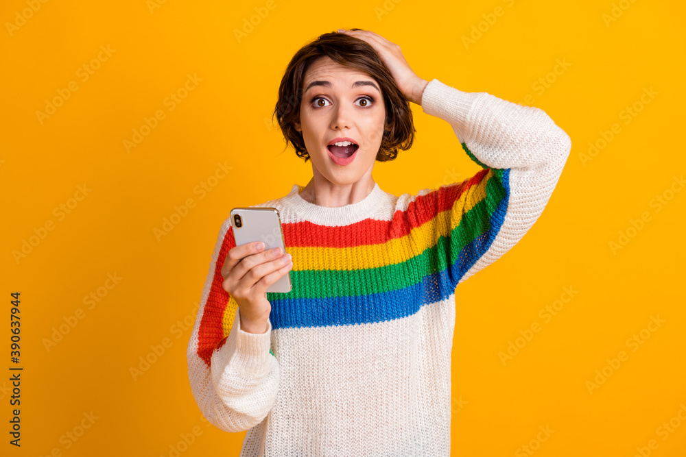 Photo of surprised girl hold smartphone arm head open mouth wear striped pullover isolated yellow color background Photo of surprised girl hold smartphone arm head open mouth wear striped pullover isolated yellow color background