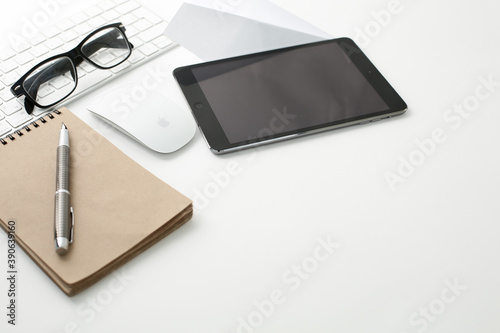 Office workplace with keyboard, notepad, tablet glasses and pen