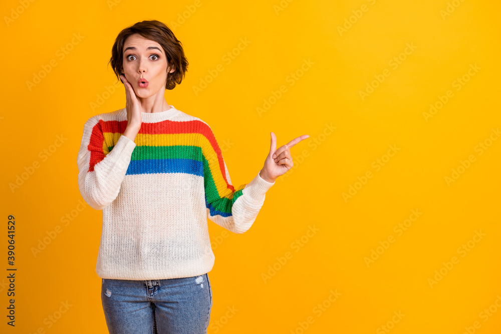 Photo of surprised pretty brunette bob hairstyle girl stand point empty space wear rainbow sweater hand cheek isolated on yellow background Photo of surprised pretty brunette bob hairstyle girl stand point empty space wear rainbow sweater hand cheek isolated on yellow background