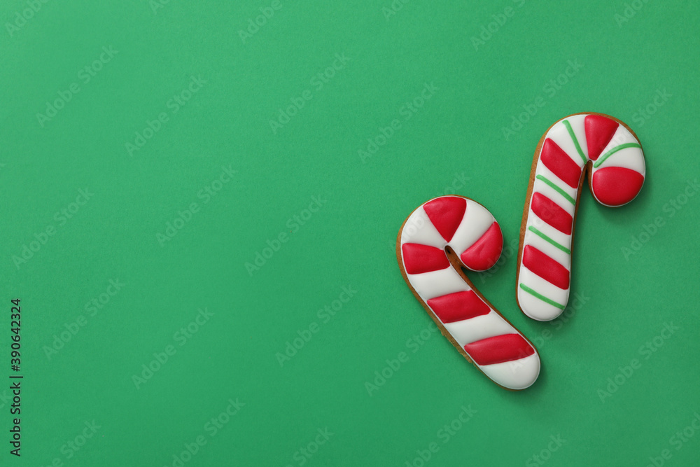 Christmas candy cane shaped gingerbread cookies on green background, flat lay. Space for text